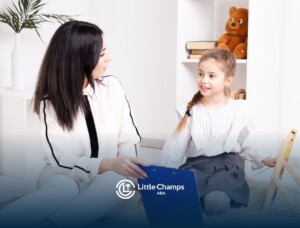 Autistic child sitting on the floor with ABA therapist, both smiling.
