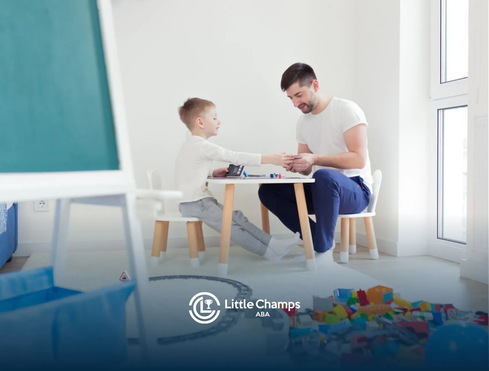 ABA therapist and autistic child playing together at a table.