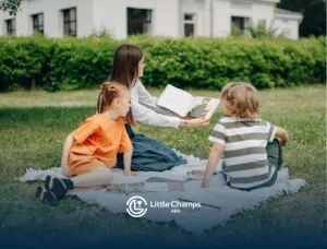 An ABA therapist reading a book to two autistic children sitting outside on a blanket in Colorado.