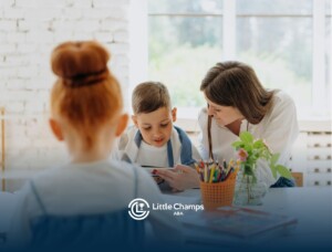 ABA therapist helping an autistic boy with workbook while another girl watches at a classroom in CO.