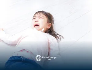 A little girl crying on the floor.