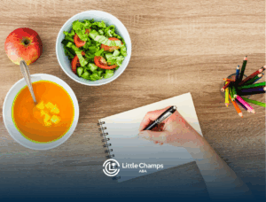 A person jotting down notes on a notepad on a table with bowls of healthy meals