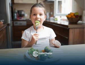 A little girl eating a plate of broccoli
