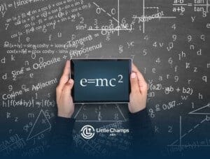 Hands hold a tablet displaying e=mc² against a chalkboard filled with mathematical equations and formulas.