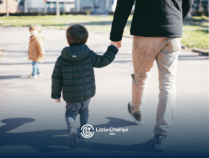 A child and his parent walking together outdoors while holding hands