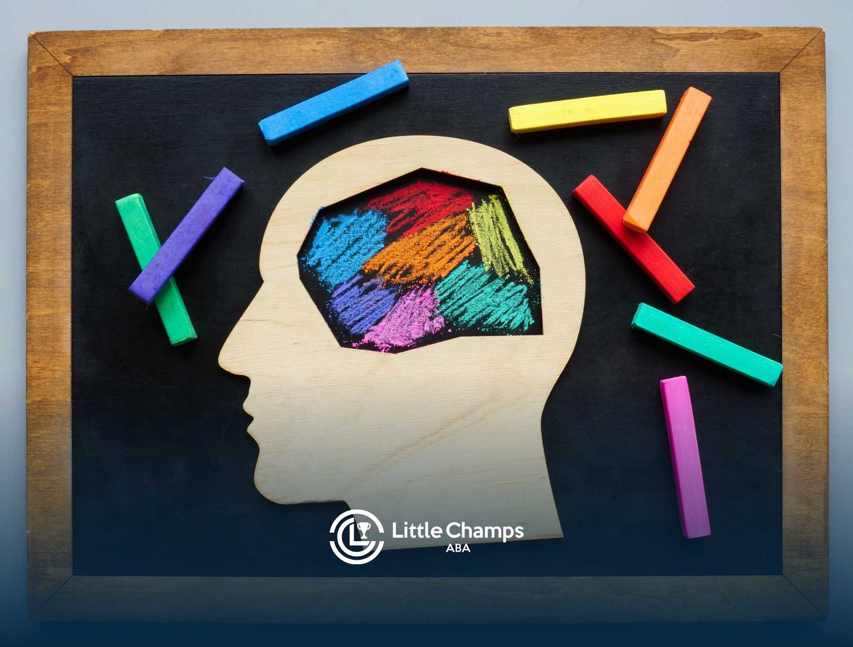 A wooden head silhouette with multicolored chalk drawing inside, surrounded by vibrant chalk pieces on a blackboard.