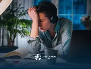 A boy wearing headphones looking frustrated, holding his forehead.