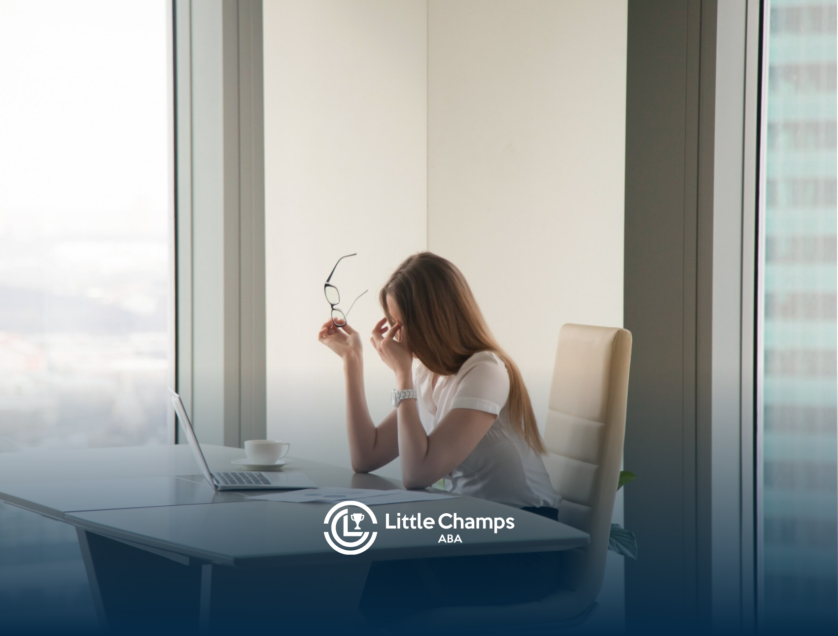 An adult with autism sitting on a desk in an office rubbing her eyes
