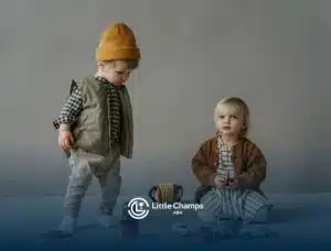 Two autistic toddlers sitting and standing near toy cars and puzzles on a gray floor in Colorado.