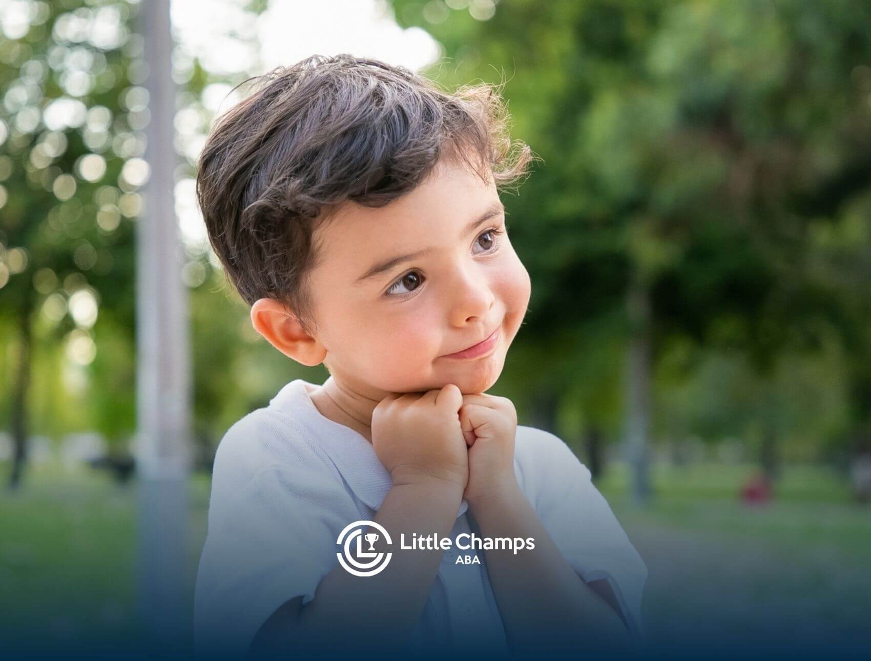 Autistic boy smiling sweetly with his hands under his chin after ABA therapy.