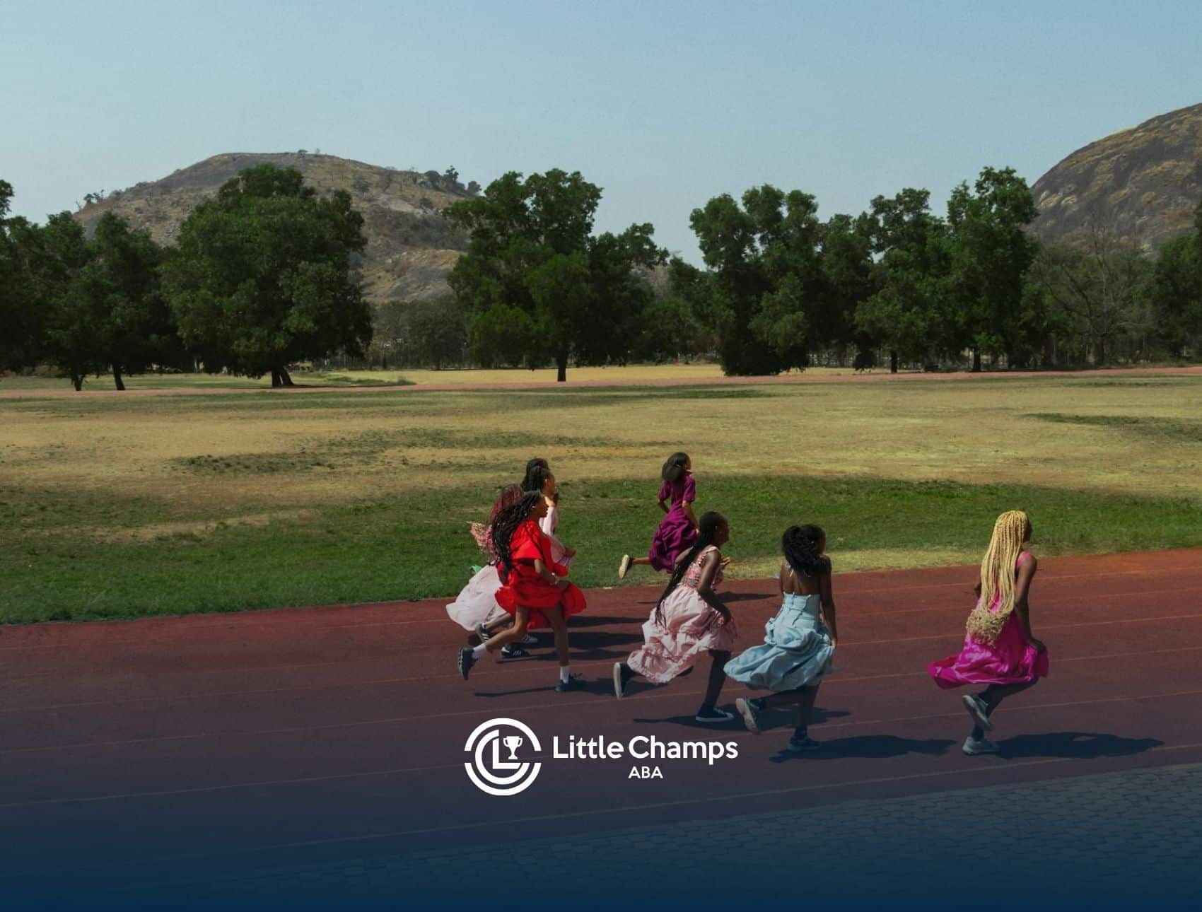 Group of autistic children running in bright dresses on a red track field outdoors in Colorado.