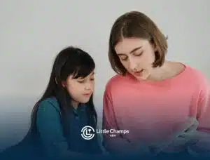 A BCBA reading or explaining something to a young girl while sitting together in ABA therapy.