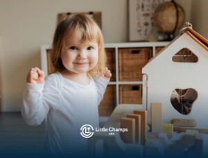 Smiling autistic toddler playing with wooden dollhouse toys during ABA therapy session in Colorado.