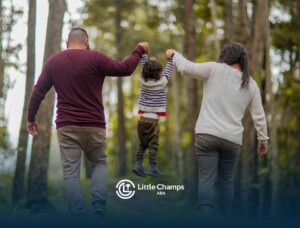 Parents swinging autistic child by arms during forest walk after ABA therapy session in Colorado.