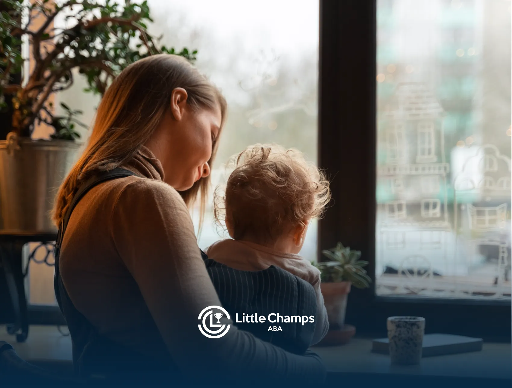 A mother and her child with autism sitting at a table by the window