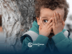 A child with autism peaking through his hands covering his face
