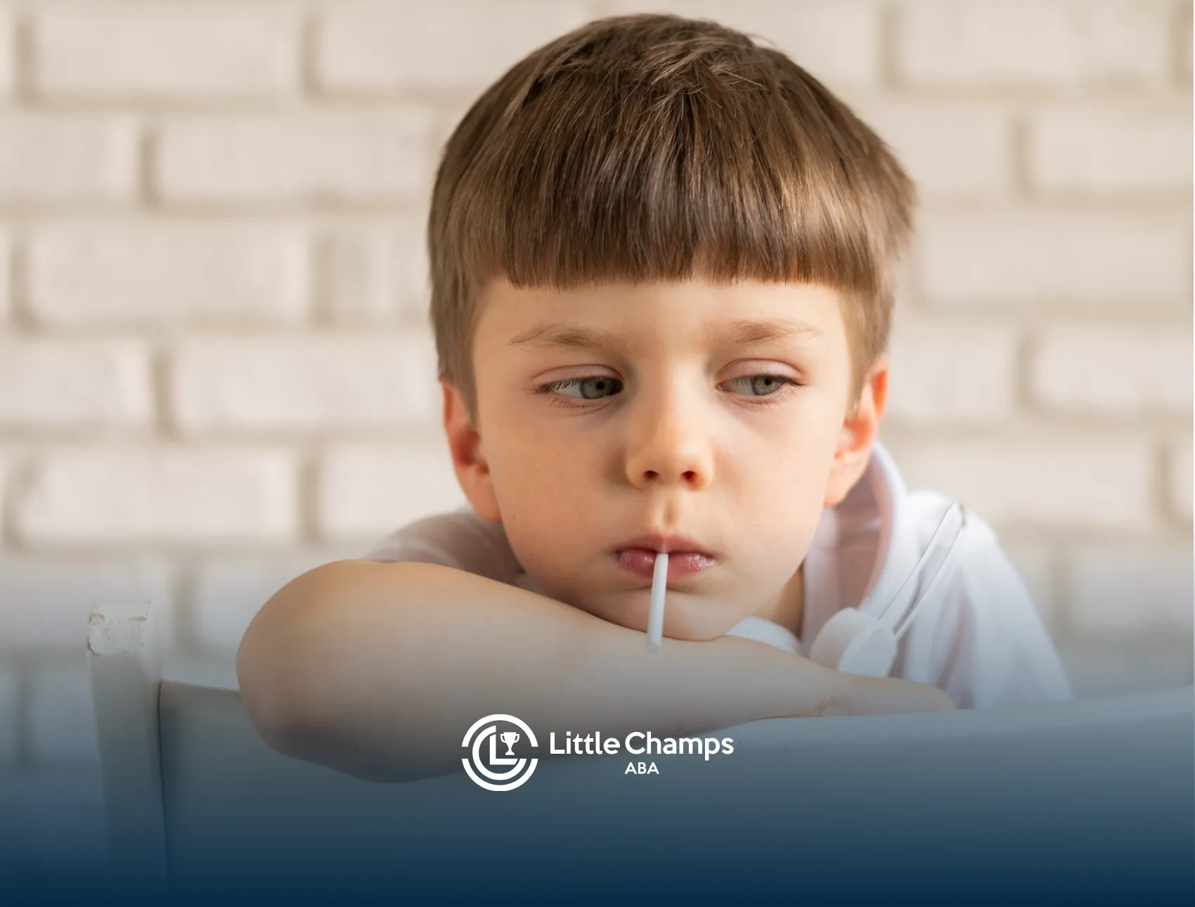 A boy is sitting on a chair sucking a lollipop