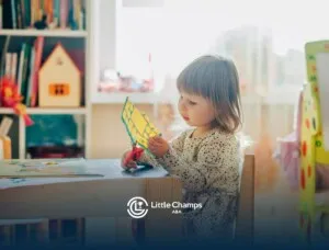 An autistic toddler cutting colored paper with scissors at desk during ABA therapy in Colorado.