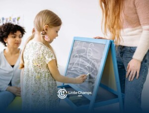 Girl writing numbers on chalkboard during ABA therapy session with BCBA and RBT nearby in Utah.