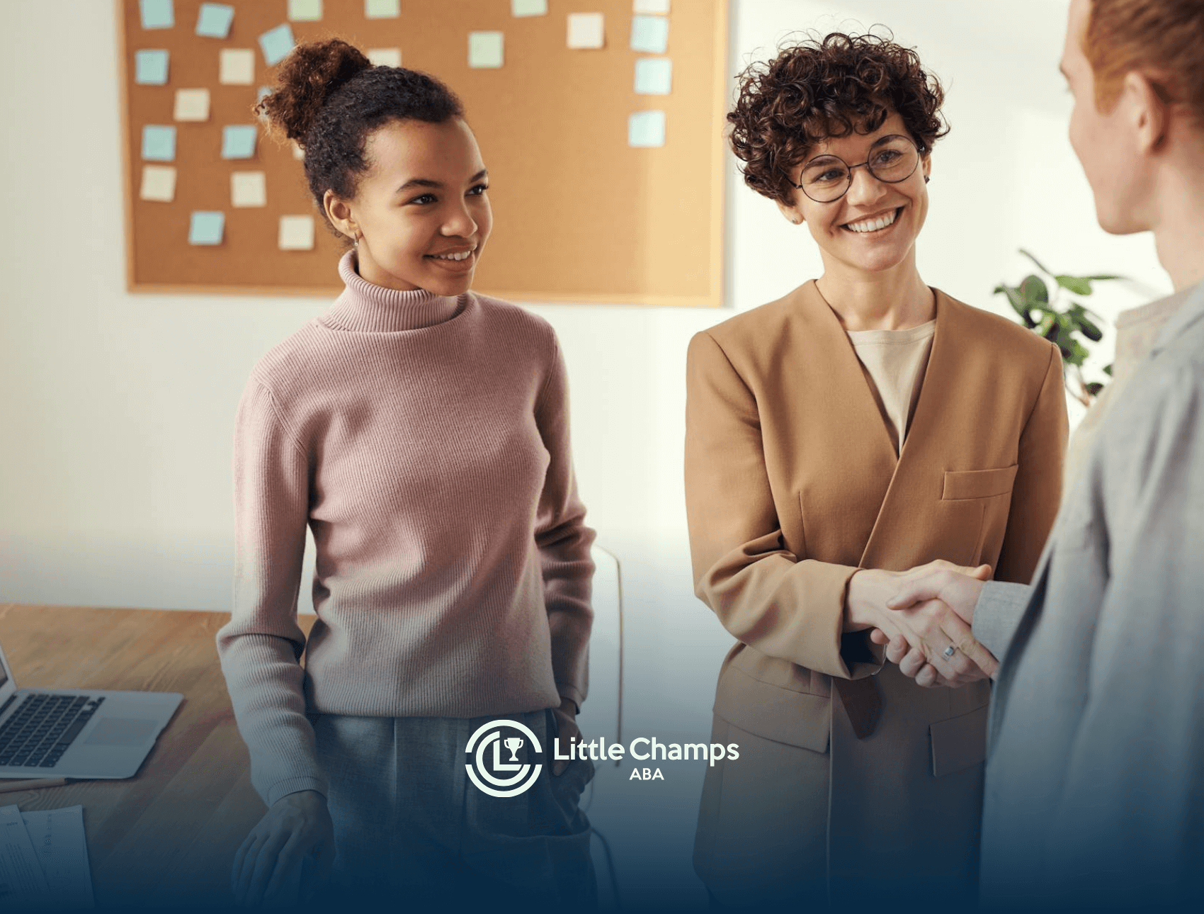 Two women shaking hands in a professional office setting, smiling and interacting with a newly hired autistic employee in CO.