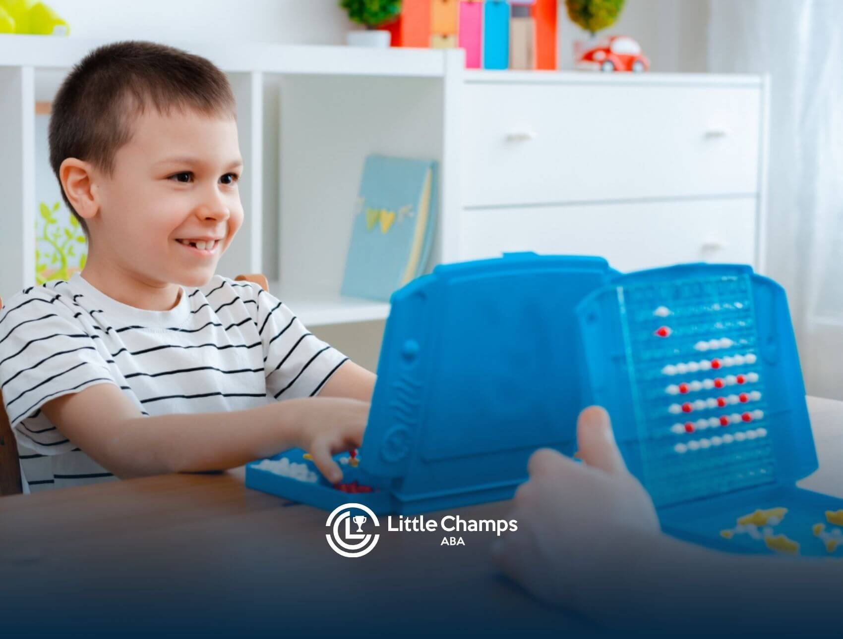 Boy with autism smiling while playing a board game in ABA therapy.