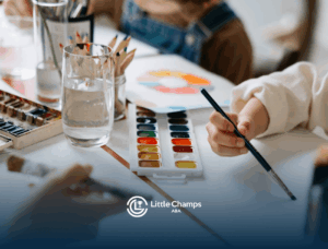 An autistic children painting with watercolors and brushes on a shared table during ABA therapy in Utah.