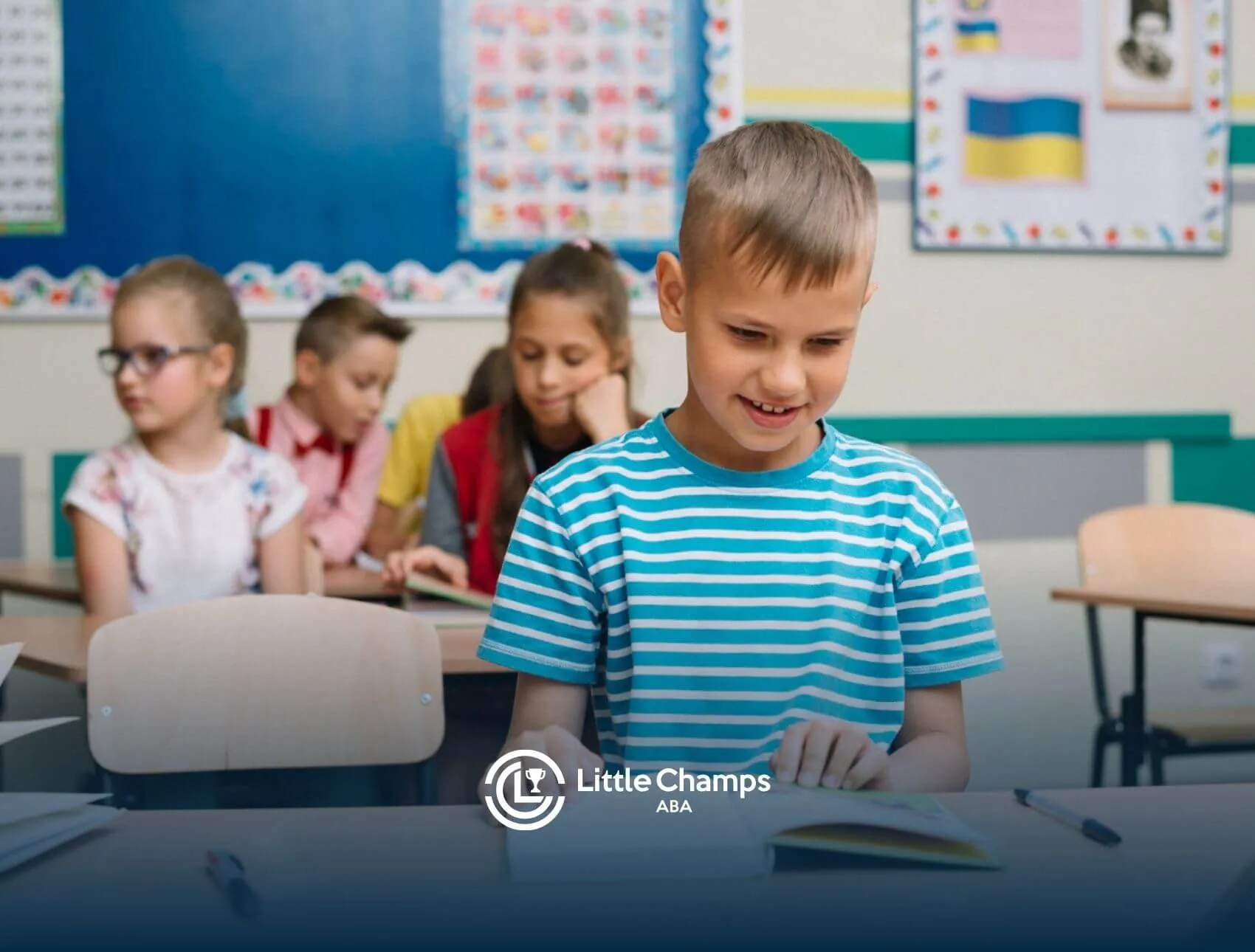 Autistic boy in a striped shirt reading a book at his desk in a classroom.