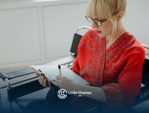 A BCBA in red writing on a clipboard, creating a behavior intervention plan, while seated indoors in Utah.