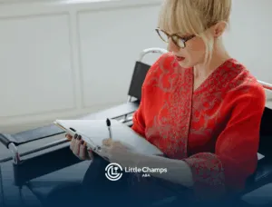 A BCBA in red writing on a clipboard, creating a behavior intervention plan, while seated indoors in Utah.