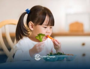 A child with autism eating vegetables at the table.