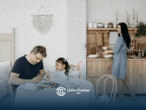 Father and his autistic daughter drawing at a table while mother cooks during parent involvement in ABA therapy in UT.