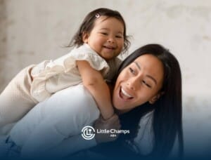 Toddler playing on BCBA's back, both smiling in ABA therapy.