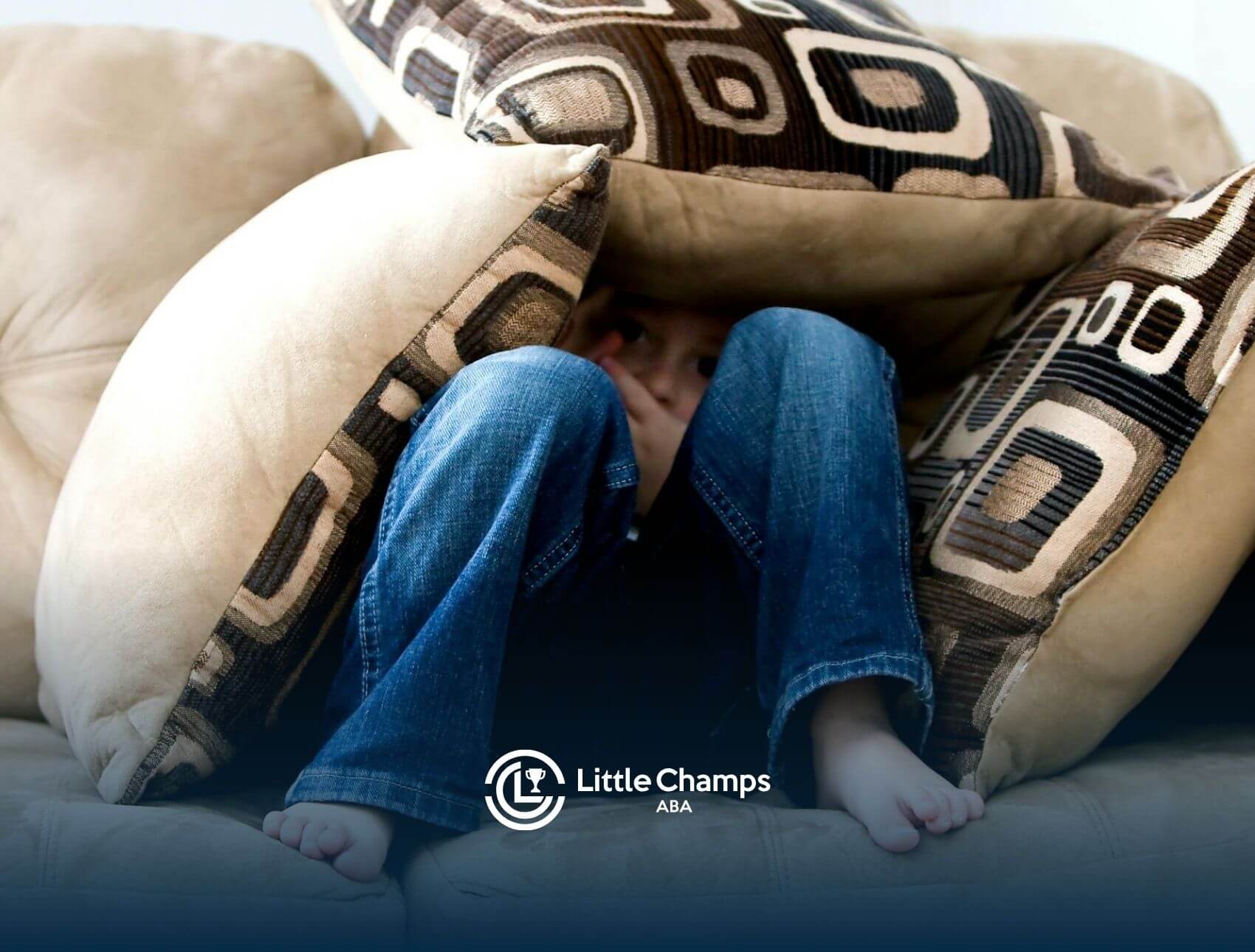 Autistic child hiding under couch cushions with only legs and face partially visible after therapy in Colorado.