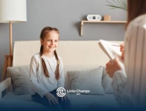 Girl with braids smiling while talking to BCBA in ABA therapy.
