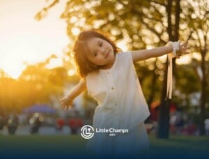 Little autistic kid playing outdoors at sunset with arms outstretched in the park after ABA therapy.
