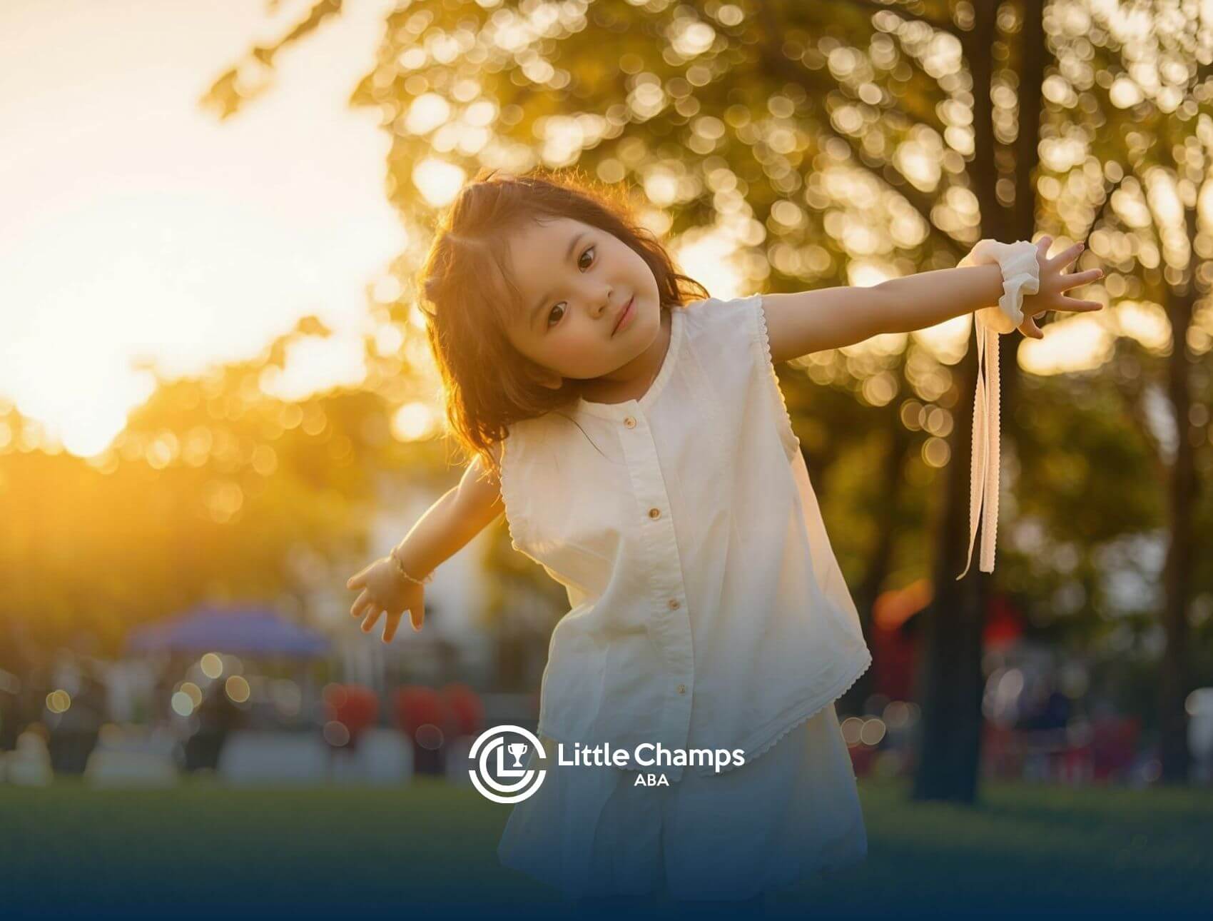 Little autistic kid playing outdoors at sunset with arms outstretched in the park after ABA therapy.