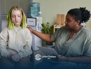 Teen with autism sitting with a therapist who gently rests a hand on their shoulder during a session.