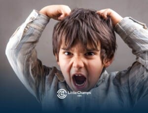 A young autistic boy with messy hair, showing frustration while pulling his hair in distress during ABA therapy.