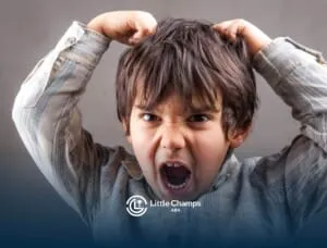 A young autistic boy with messy hair, showing frustration while pulling his hair in distress during ABA therapy.