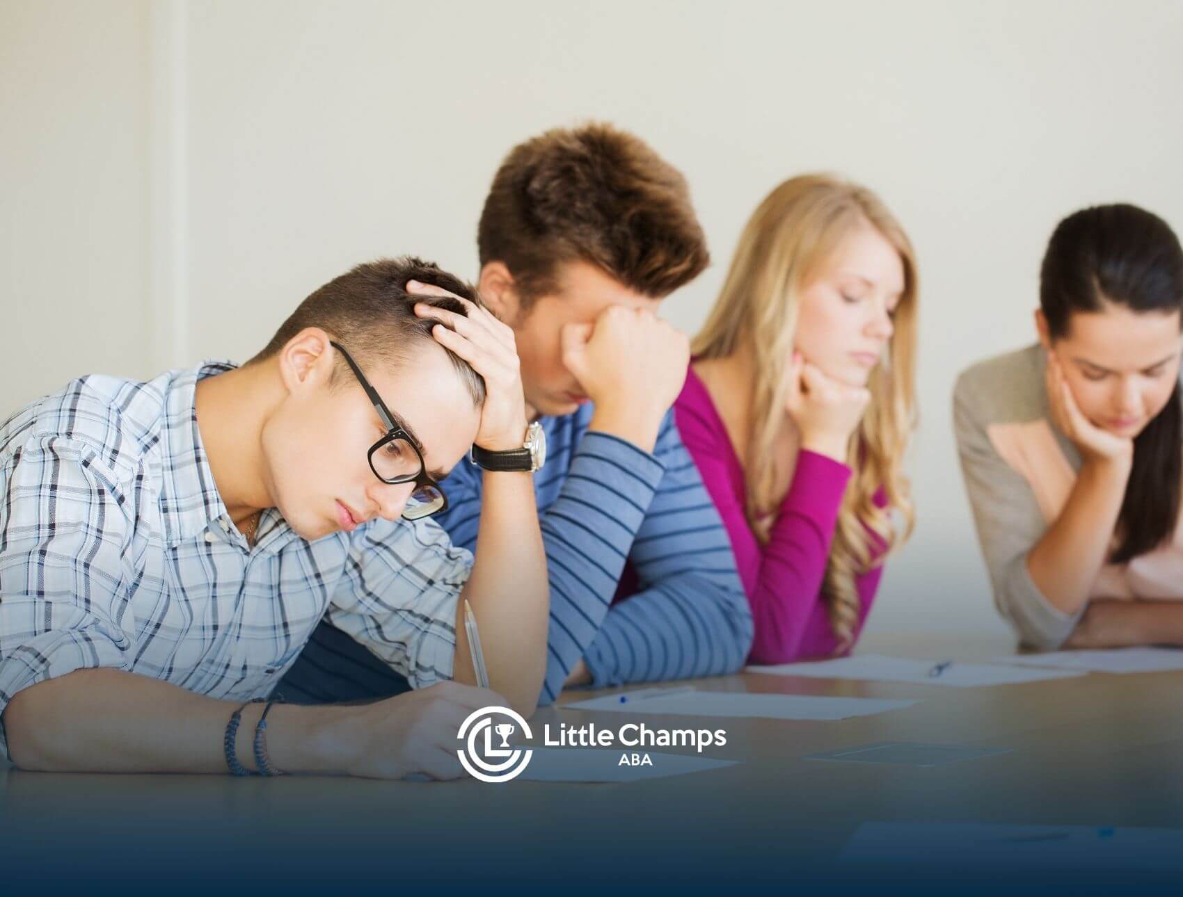 A group of young adults looking stressed while sitting around a table during a work or study session.