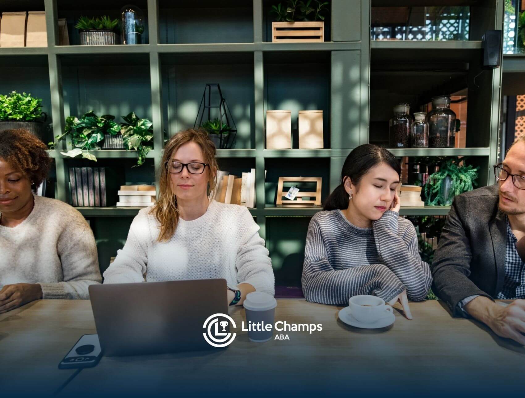 A group of people working in a modern coffee shop setting, with laptops, coffee cups, and focused expressions.