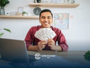 A Male ABA therapist holding a fan of cash, sitting at a desk with papers, smiling in an office setting.
