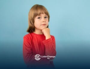 Thoughtful young child with autism in a red shirt posing with hand on chin against a light blue background.