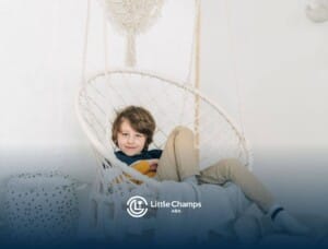 Boy with autism sitting comfortably in a hanging chair during ABA therapy, smiling at the camera.