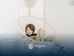 Boy with autism sitting comfortably in a hanging chair during ABA therapy, smiling at the camera.
