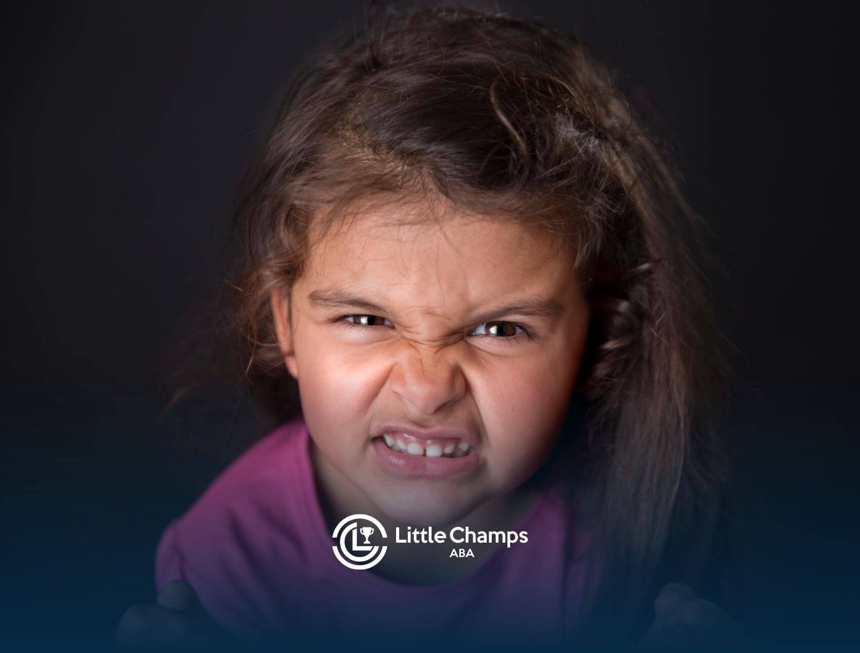 Close-up of a young girl with a fierce, angry facial expression during ABA therapy.