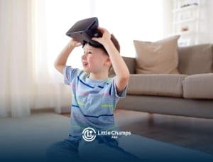 Young child smiling while holding a virtual reality headset above his head in a living room during ABA therapy.