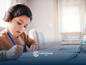 Young boy with autism wearing headphones, focused on writing in a notebook beside a laptop.