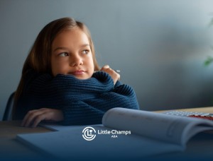 Child resting chin on arms at a desk during ABA therapy.