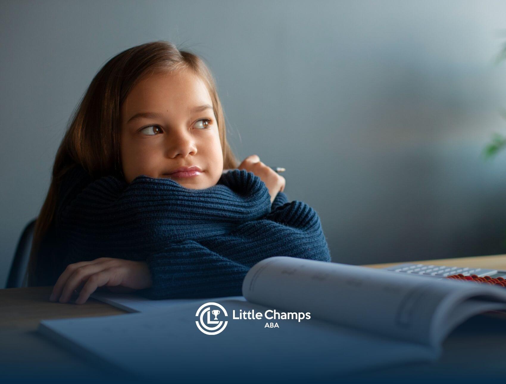 Child resting chin on arms at a desk during ABA therapy.